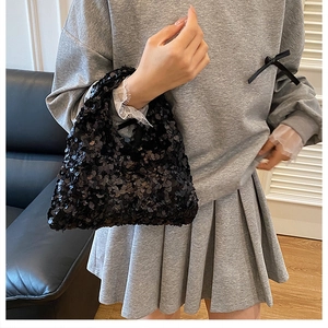 Close-up of black sequined handbag styled with a trendy casual outfit on a leather sofa