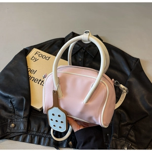 Detail of pink and white macaron bowling bag with dual handles and cutout charm