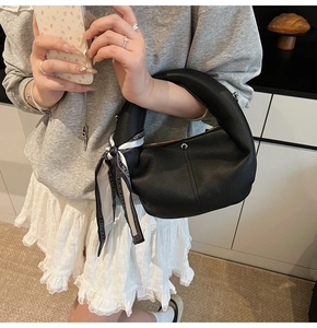 Detail view of black lychee leather handbag with decorative printed silk scarf on handle