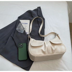 Detail view of cream-white leather shoulder bag with pleated design on white sheets