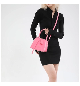 Detailed close-up of glossy pink shell-shaped patent leather crossbody bag with gold accents