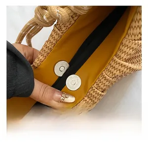 Macro shot of silver magnetic snap closures and yellow lining inside a woven bag