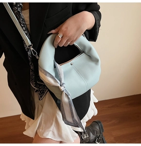 Chic light blue leather handbag with silk scarf detail and adjustable shoulder strap
