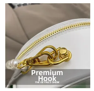 Close-up of premium gold-plated hooks and zipper details on white leather evening bag