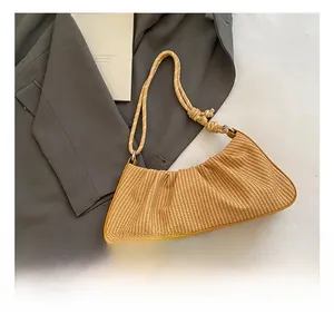 Detail of yellow woven cloud bag with knot rope handle and straw texture on blazer