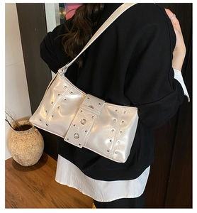 Detailed view of cream faux leather shoulder bag with silver studs on model back