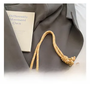 Detail of yellow braided rope handle with silver metal clip on a textured bag