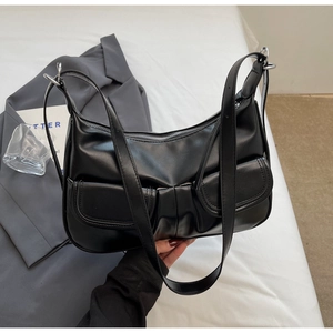 Detail of minimalist black hobo bag with dual front flap pockets and silver metal rings