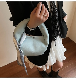 Detail of light blue lychee pattern half-moon handbag with silk scarf on the handle