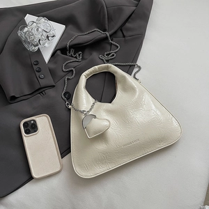 Chic cream ruched leather handbag with metal chain and heart pouch on a stylish blazer