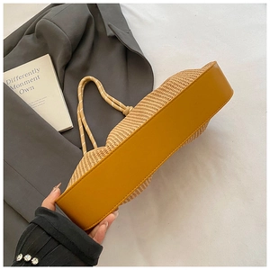 Detail of woven straw handbag featuring yellow leather bottom and rope handle accents