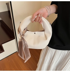 Close-up of white pebble leather hobo bag with elegant patterned silk scarf detail