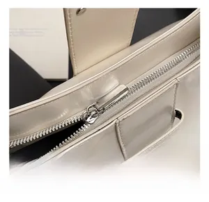 Detailed macro view of ivory leather handbag showing polished silver zipper and hardware