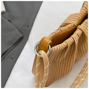 Macro detail of ginger yellow woven texture and pleated cloud design on shoulder bag