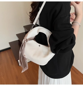 Detail of white lychee texture handbag featuring silk scarf handle and metal accents