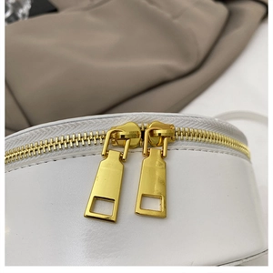 Detail shot of the shiny gold double metal zippers on this white round crossbody evening bag