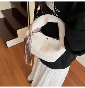 Close-up of white lychee textured bag with silver buckle and decorative silk scarf