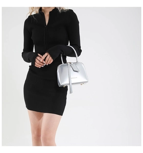 Detail of silver metallic shell bag with leather tassels and handle on black dress