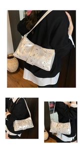 Detailed view of the pearly white shoulder bag featuring vintage metallic studs and glossy finish