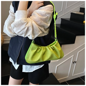 Detail of neon green woven dumpling bag with knot shoulder strap on model