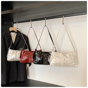 Detail showing four glossy patent leather bags with metal rivets and large eyelet buckles
