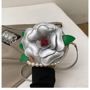 Detail view of a 3D silver flower bag with red center and white pearl handle