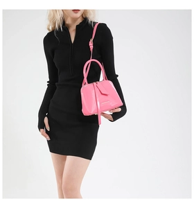 Detail of pink glossy patent leather shell bag with shoulder strap and embossed text