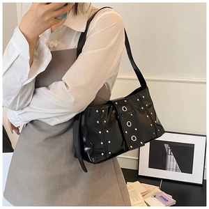 Detail of black glossy shoulder bag featuring punk silver rivets and large metal eyelets