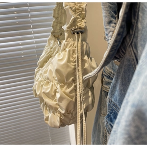 Detail shot of beige ruched cloud bag with drawstring texture and metal hardware