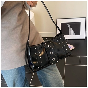 Close-up of black patent leather shoulder bag with punk style silver rivets and eyelets