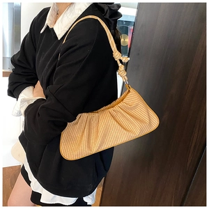 Detailed view of straw-woven dumpling bag with cloud pleats and knotted shoulder strap