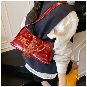 Detail of red patent leather shoulder bag with silver rivets and metal buckle hardware