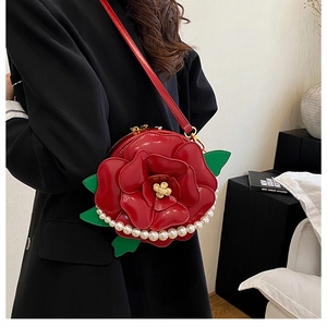 Detail of red flower bag with pearl trim, green leaf accents and gold hardware