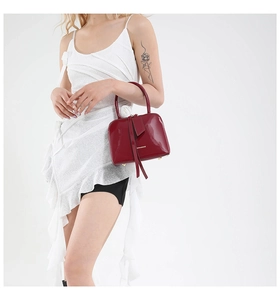 Detail of burgundy patent leather handbag with gold Robinmay logo and sleek handles