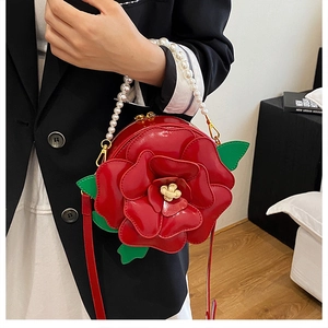 Close-up of red rose flower handbag with pearl handle and green leaf detail