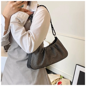 Detail of woven fabric texture and pleated crescent design on stylish underarm bag