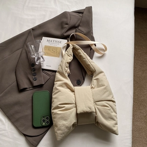 Chic beige bow-shaped nylon puffer tote bag with wide strap on minimalist background