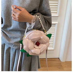 Detail of camellia flower bag with pearl handle and pink petals for wedding party