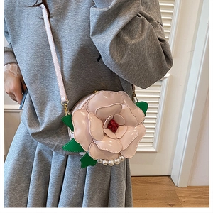 Detail of pink flower petal shoulder bag with white pearl trim and green leaf accents