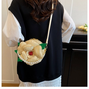 Detail of cream camellia floral crossbody bag with pearl strap and golden hardware
