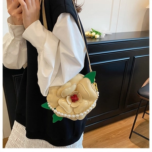 Detail of camellia floral crossbody bag with pearl trim and green leaf accents