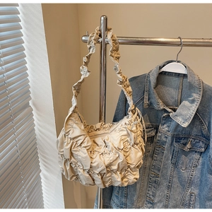 Close-up of beige puff cloud bag with gathered pleated texture hanging on a metal rack