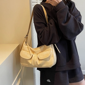 Minimalist beige dumpling shoulder bag with front pockets on a waffle texture outfit