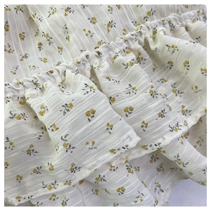 Macro detail of floral fabric with yellow blossoms and pleated ruffles on a tote bag