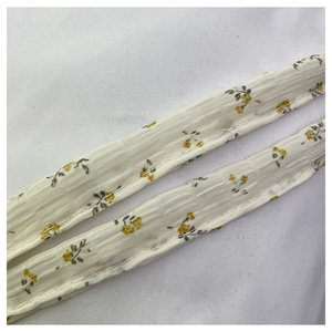 Detailed close-up of slim shoulder straps with yellow floral print on cotton fabric