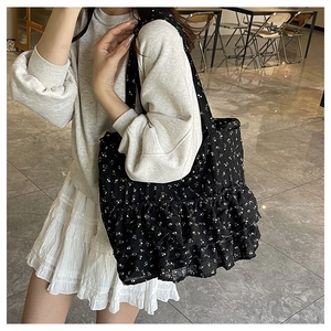 Detail of a black floral tote bag with double ruffles and intricate flower patterns