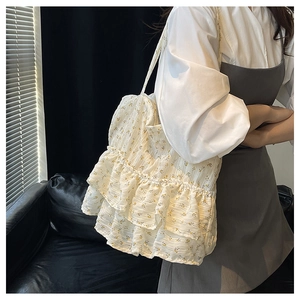 Floral fabric tote bag with ruffled layers worn by model in a stylish indoor setting