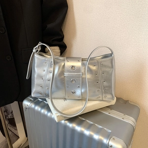 Silver metallic underarm bag with decorative rivets and buckles in a fashion setting