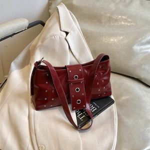 Burgundy red leather shoulder bag with silver studs and eyelets on white blazer