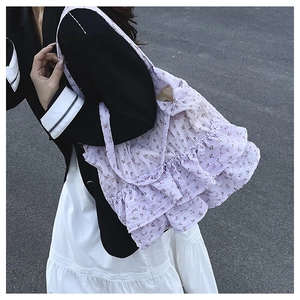 Detail of purple floral tote bag featuring layered ruffles and delicate red flower pattern